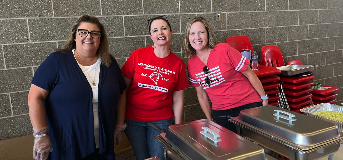 three alumni and friends woman posing for a picture in front of food at a SPCS thank you event